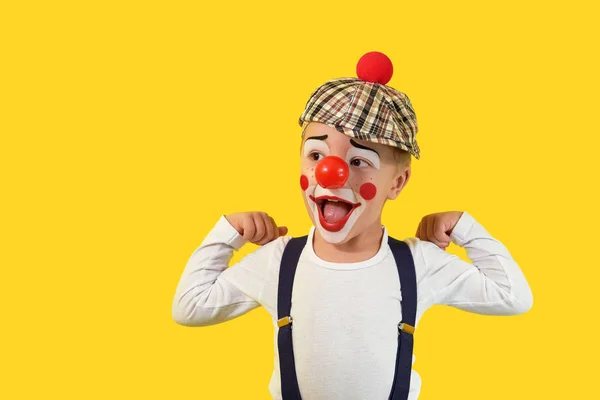 Ritratto divertente bambino.Ragazzo allegro, clown costume, naso rosso, trucco.Faccia emotiva piccolo bambino comico.Felice bambino isolato sfondo giallo. concetto compleanno, vacanza, umorismo . — Foto Stock