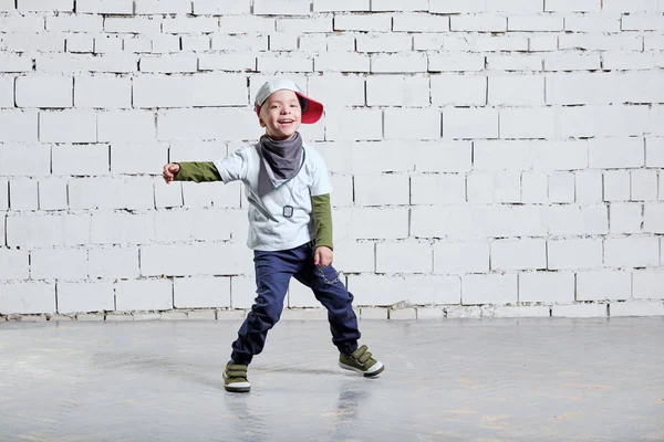 çocuk çocuk müzik dans. Cool çocuk hip hop. Şirin moda yaramaz çocuk. Rapçi ufaklık şapkası, spor ayakkabı, pantolon, tişört, sokak stili kıyafetler giyer. Stüdyo, tuğla duvar arka plan.