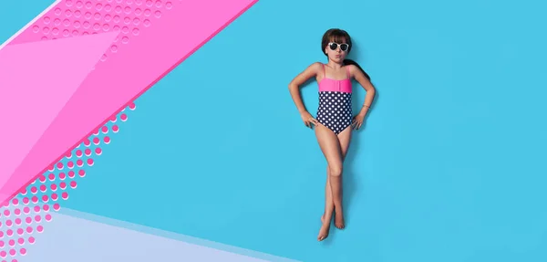 Moda çocuk yaz. Mayo giymiş küçük kız çocuk üstte yatıyordu. Konsept plaj tatili. Boş, afiş, reklam için kopya alanı. Stüdyoda deniz suyu gibi izole pembe, mavi renkli arka plan.