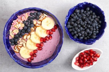 Sağlıklı blueberry smoothie kaseyle bannan, el bombası, badem, darı bulamaç.