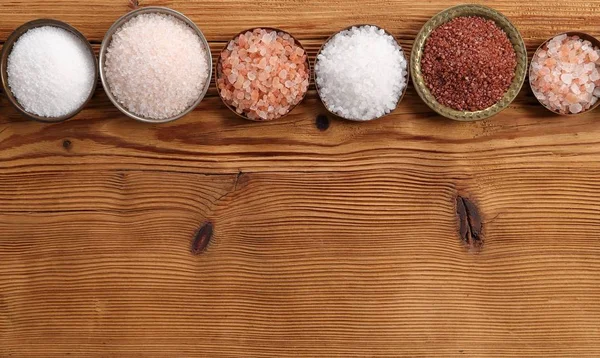木製の背景にボウルに食卓塩の様々 なタイプ トップ ビュー — ストック写真