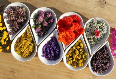 Bitkiler ve çiçekler ahşap arka plan üzerinde seramik kase doğal alternatif ilaçlar kullanılır. Üstten görünüm. Düz yatıyordu.