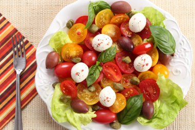 Renkli domates mozzarella peynir, zeytin, kapari ve fesleğen salata. Üstten görünüm.