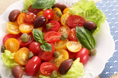 Renkli domates, zeytin, kapari ve fesleğen salata. Üstten görünüm.