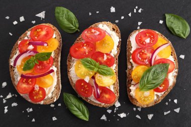 Peynir, renkli domates, fesleğen ve soğan ile sandviçler. Üstten görünüm.