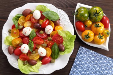 Renkli domates mozzarella peynir, zeytin, kapari ve fesleğen salata. Üstten görünüm.