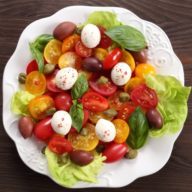 Renkli domates mozzarella peynir, zeytin, kapari ve fesleğen salata. Üstten görünüm.