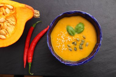 Siyah arka plan üzerine bir kapta balkabağı çorbası. Üstten görünüm.