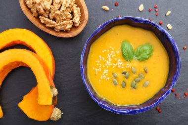 Siyah arka plan üzerine bir kapta balkabağı çorbası. Üstten görünüm.