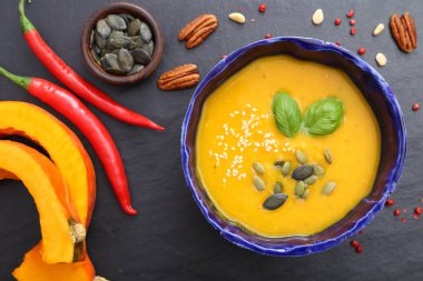 Siyah arka plan üzerine bir kapta balkabağı çorbası. Üstten görünüm.