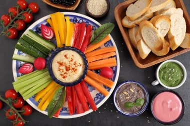 Bir tabak ve humus türleri şeritler halinde kesilmiş renkli taze sebze.
