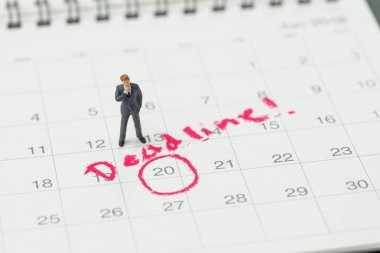 Minyatür iş adamı kırmızı cir ile masaüstü takvimüzerinde duran