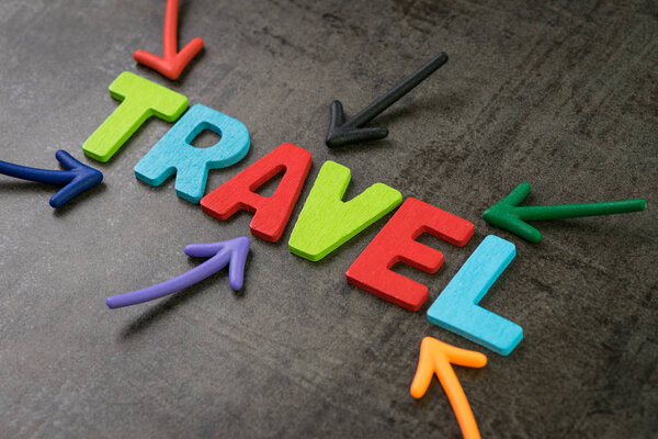 Travel, tourism concept, colorful arrows pointing to the word Travel at the center of black chalkboard wall, new trend for people to travel the world to gain happiness.