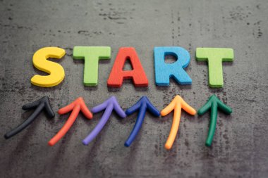 İş başlangıç veya yeni bir yaşam yolculuğu kavramı başlar, renkli oklar kelime başlangıç tahta çimento duvara başlangıç noktası başlatma düşünme, cesur ve kutunun dışında düşünmek önemli vurgulamak için.