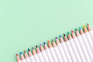 Kopya ile pastel yeşil kağıt arka plan üzerinde canlı renkli kalemler