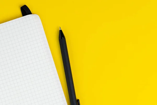 Άνοιγμα ενός κενού σημειωματαρίου σελίδας χαρτιού γραφήματος με πένα σε στερεό κίτρινο — Φωτογραφία Αρχείου