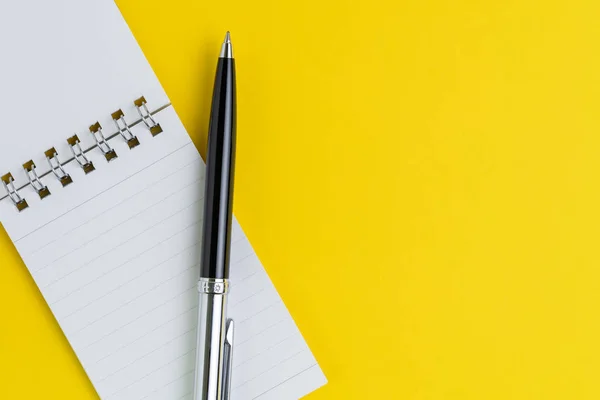 Små papper anteckningsblock med tom sida, penna på solid Yellow backgro — Stockfoto