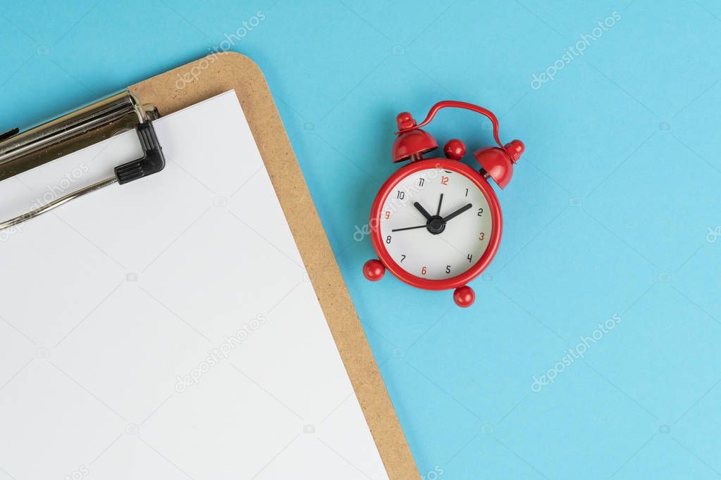 Clipboard with empty white paper with read alarm clock on solid 