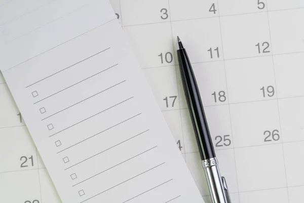 Ручка в контрольном списке с блокнотом в чистом календаре с помощью — стоковое фото