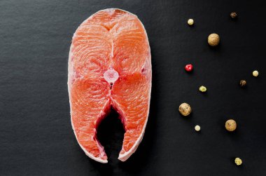 Dilim çiğ pembe somon Steak üzerinde siyah arka plan üstten görünüm. 