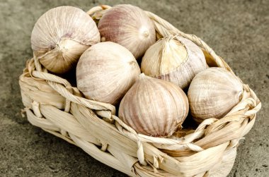 Doğal taş yüzeyinde bir sepet içinde sarımsak ampuller. Rustik tarzı.