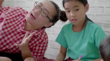 Asyalı anne oturma odasında çocuklarla oynuyor..