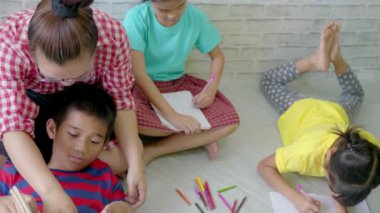 Asyalı anne oturma odasında çocuklarla oynuyor..