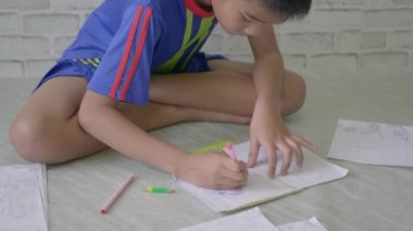 Asyalı çocuk kağıt üzerine kalem çiziyor, günlük yaşam tarzı videosu..
