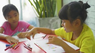 Asyalı çocukların küçük kızları evde ders çalışıyorlar ve bir deftere yazıyorlar..