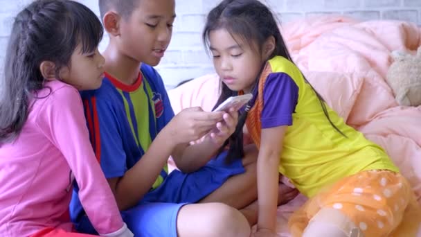 幼い子供たちが自宅でスマートフォンを使って — ストック動画