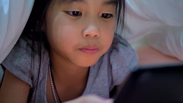 Asyalı Çocukların Küçük Kızı Yatakta Battaniyenin Altında Tablet Kullanıyor — Stok video
