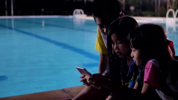 Asiatische Kindergruppe Entspannt Sich Abends Mit Smartphone Schwimmbadnähe — Stockvideo