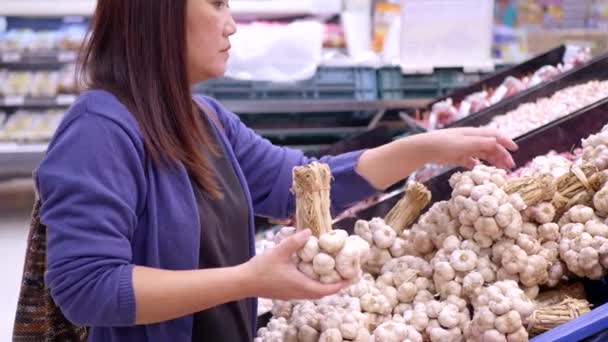 在杂货店选大蒜的亚洲女人 — 图库视频影像