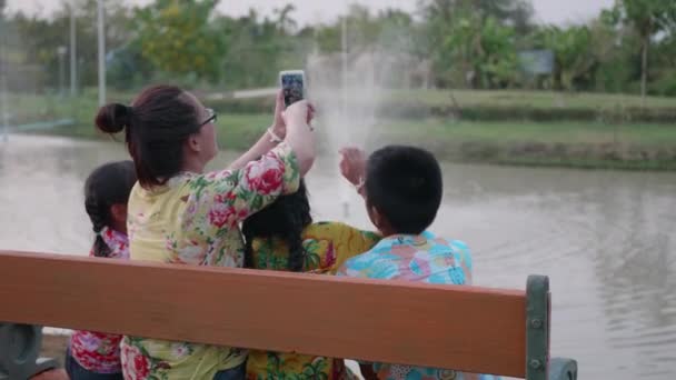 公共公園でスマートフォンで自撮りしている幸せなアジアの家族 — ストック動画