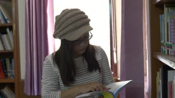 Aziatische Vrouw Staan Achterkant Van Boekenplanken Het Lezen Van Boek — Stockvideo