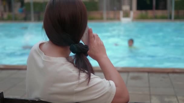 Mujer Asiática Usando Teléfono Celular Cerca Piscina Esperando Hija — Vídeo de stock