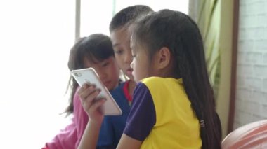Asyalı çocuk grubu evde akıllı telefon kullanıyor..
