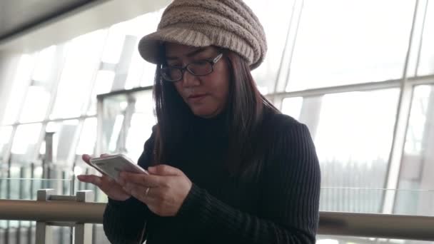 Azjatka Stojąca Przy Dużym Oknie Terminalu Lotniska Korzystająca Smartfona — Wideo stockowe