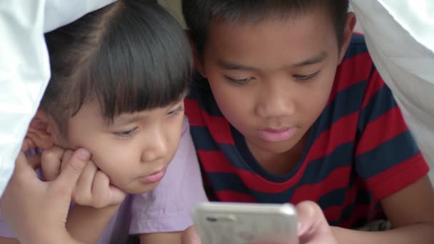 Niños Asiáticos Usando Teléfono Inteligente Tableta Debajo Manta Cama — Vídeo de stock