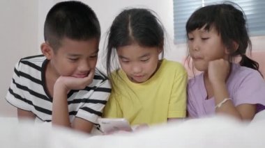 Yatak odasında akıllı telefon kullanan Asyalı çocuklar..