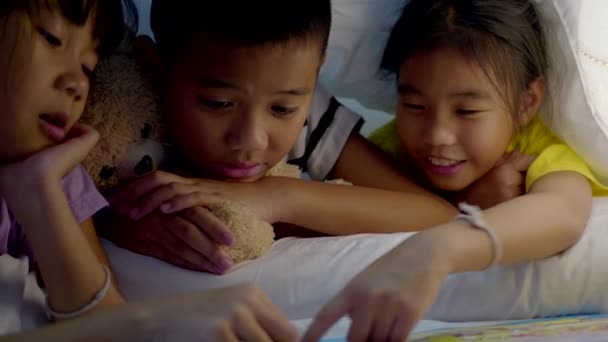 アジアの子供たちのグループは 自宅でベッドルームで物語を読む — ストック動画
