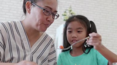 Mutlu Asyalı çocuklar annesi için lezzetli salata yiyor..