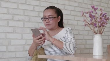 Restoranda akıllı telefon kullanan Asyalı kadın..
