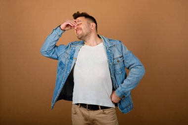 Yakışıklı adam ayakta ve gülümsüyor açık kahverengi stüdyo arka planında izole edilmiş. Yarım boy erkek portresi. İnsan duyguları, yüz ifadesi konsepti..