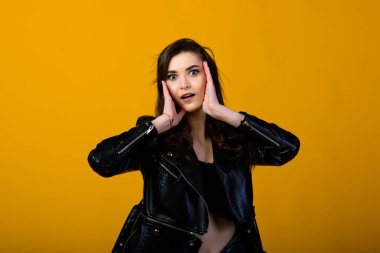 Mutlu, esmer bir kızın portresi jestler ve gülücükler gösteriyor, sarı arka planda izole edilmiş şaşırtıcı bir şekilde. Duygusal resim