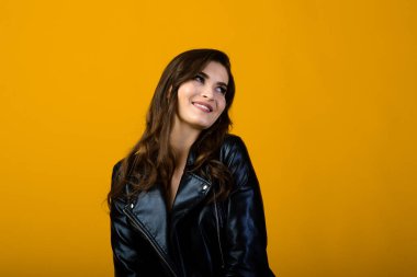 Mutlu, esmer bir kızın portresi jestler ve gülücükler gösteriyor, sarı arka planda izole edilmiş şaşırtıcı bir şekilde. Duygusal resim