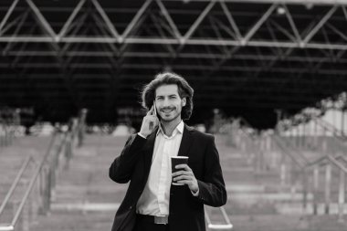 Yakışıklı bir işadamının portresi telefon ve kahve fincanı şehir sokaklarında.