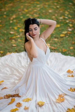 Güz parkında uzun beyaz elbiseli güzel esmer kadın..