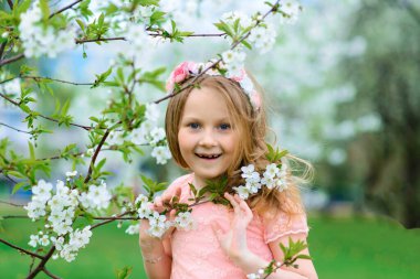 Prenses elbisesi giymiş şirin küçük bir kızın açık hava portresi. Çiçek açan bahçe, duygusal fotoğraf.