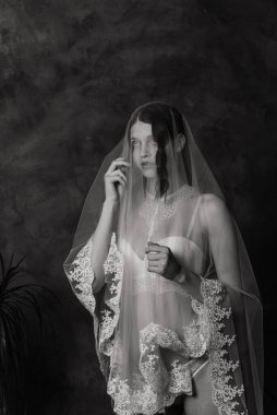 Beyaz iç çamaşırlı güzel gelin yatak odasında ve stüdyosunda oturuyor. Düğün konseptinin sabahı